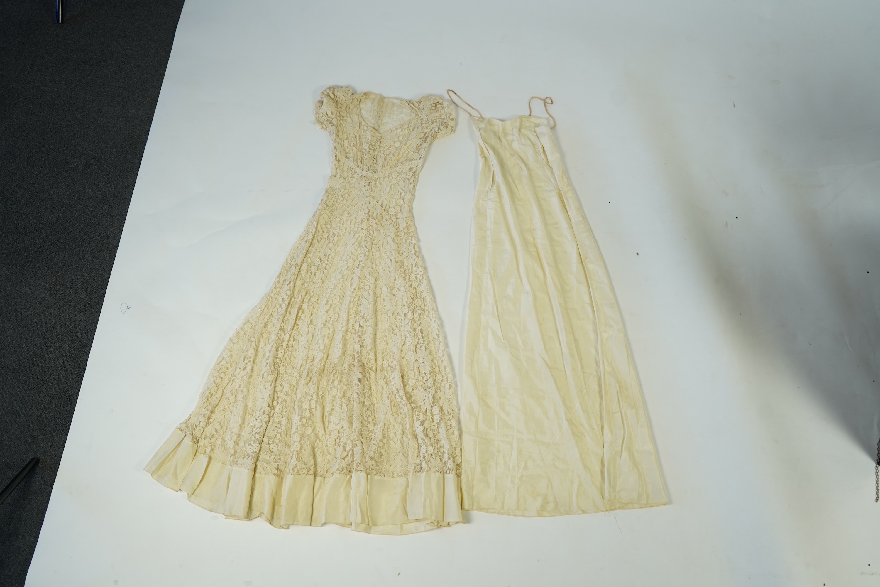 An early 1940's cream cotton lace and taffeta evening dress, with matching taffeta petticoat, possibly worn as a wedding dress., Dress 144cm long. Condition - minor repairs needed to lace in places and laundering to remo